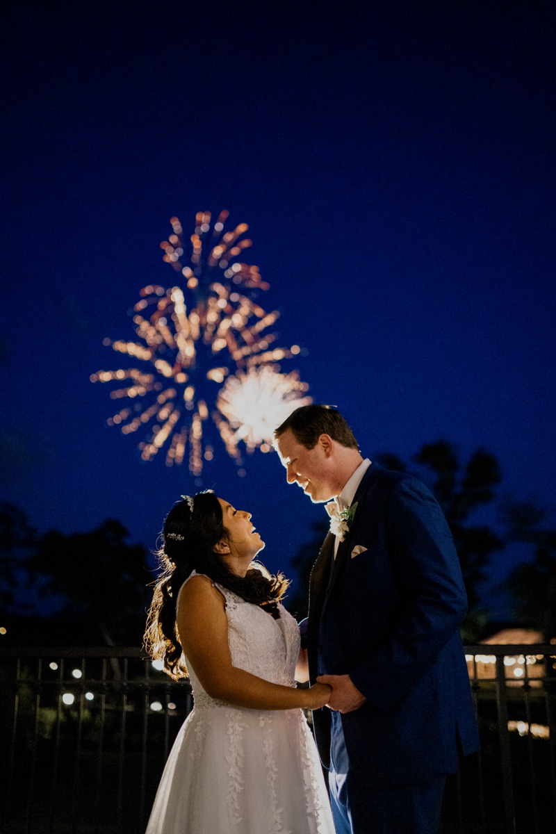 A Live Picture Studios couple smiling together beneath wedding-night fireworks